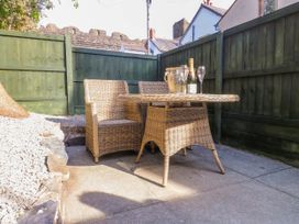 An outdoor seating area with a wicker table and chairs a bottle of champagne and glasses at 6 Uppergate Street Rose Cottage in Conwy
