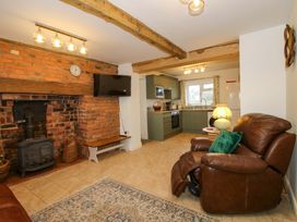 A living room with a fireplace and kitchen area at 1 Dingle Cottage in Worcester