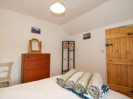 A bedroom with a bed and dresser at 1 Dingle Cottage in Worcester