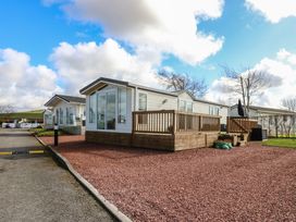 A row of white mobile homes with wooden decks on a gravel lot near a road at Plot 6 near Armathwaite