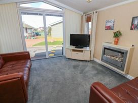 A sitting room with two leather sofas a wall-mounted fireplace and a TV on a stand near Plot 6 near Armathwaite