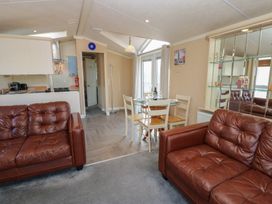 A living area with two brown leather sofas a glass dining table with four chairs and a kitchen near Armathwaite