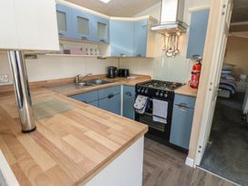 A kitchen with wooden countertops blue cabinets a black stove and a sink at Plot 6 near Armathwaite