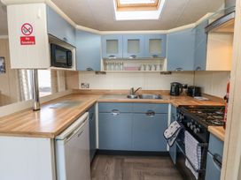 A kitchen with blue cabinets wooden countertops a sink a stove microwave and a refrigerator at Plot 6 near Armathwaite