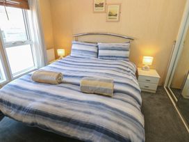 A bedroom with a double bed with striped bedding two rolled towels two bedside tables with lamps two framed pictures on wall and a mirrored wardrobe near Armathwaite