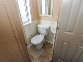A small bathroom with a toilet sink mirror window and tiled floor at Plot 6 near Armathwaite