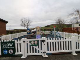 A fenced children's play area with a climbing net and slides near Armathwaite