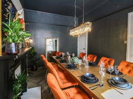 A dining room with a long table set for a meal at Fox House in Llandudno
