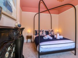 A bedroom with a four-poster bed and decorative pillows at Fox House in Llandudno