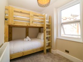 A bedroom with a bunk bed and a single bed at Fox House in Llandudno