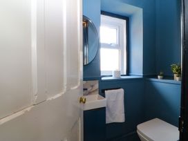 A bathroom with a toilet, sink and mirror at Fox House in Llandudno