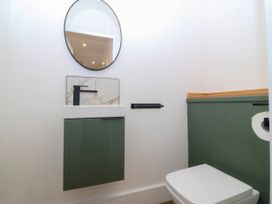 A bathroom with a sink, mirror, and toilet at Fox House in Llandudno