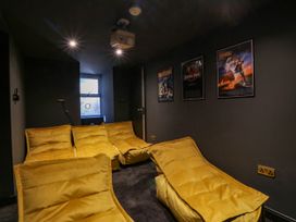 A home theater with yellow seating and movie posters at Fox House in Llandudno