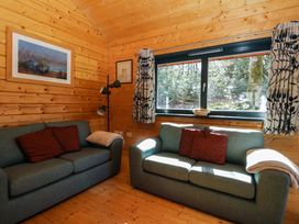 A sitting room with two sofas two framed pictures a window with curtains and a floor lamp at Esk Lodge in Salen Isle Of Mull