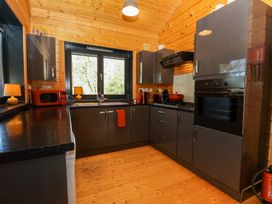 A kitchen with grey cabinets black countertops wooden ceiling and floor and red appliances at Esk Lodge in Salen Isle Of Mull