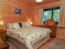 A bedroom with a bed floral bedding two bedside tables with lamps a wooden dresser and a window at Esk Lodge Salen Isle Of Mull