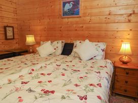 A bedroom with two beds pushed together floral bedding pillows two bedside tables with lamps and wooden walls at Esk Lodge in Salen Isle Of Mull