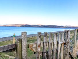 A wooden gate overlooking a beach and calm water with hills in the distance at Esk Lodge Salen Isle Of Mull