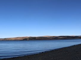 A rocky shoreline with calm water and hills in the distance at Esk Lodge Salen Isle Of Mull