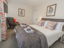 A bedroom with a bed and armchair at Shrimp Cottage in Brewers Quay Harbour