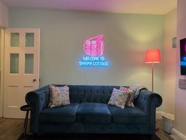 A living room with a blue sofa and a neon sign at Shrimp Cottage in Brewers Quay Harbour