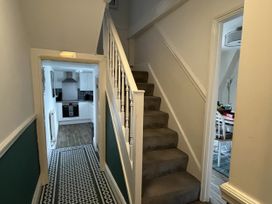 A hallway with stairs leading up and a view of the kitchen at Shrimp Cottage in Brewers Quay Harbour