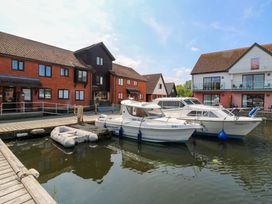 Boats at a dock next to buildings at Kingsmere in Norwich