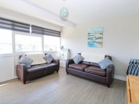 A living room with two brown leather sofas and cushions with a coastal painting on the wall at Chalet 37 in Hemsby