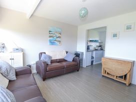 A living room with two brown sofas a wooden drop leaf table and a view into a kitchen at Chalet 37 in Hemsby