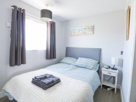 A bedroom with a double bed striped bedding folded towels on bed bedside table with lamp and clock at Chalet 37 in Hemsby