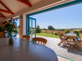 A dining room leading to a deck with outdoor seating at Little Chywoon Barn in Truro