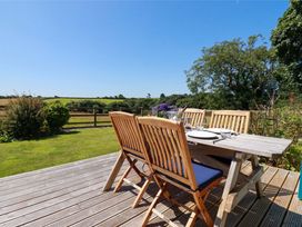 A dining table and chairs on a deck in the garden at Little Chywoon Barn Truro