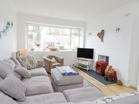 A living room with a sectional sofa an armchair a wood stove and a television at 3 Glyn Y Mor in Llanbedrog