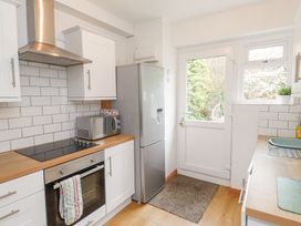 A kitchen with white cabinets a stainless steel oven and range hood a microwave on the counter and a refrigerator next to a door with a window at 3 Glyn Y Mor in Llanbedrog