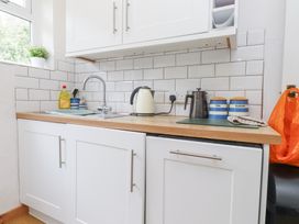 A kitchen countertop with a sink kettle tea and sugar containers at 3 Glyn Y Mor in Llanbedrog