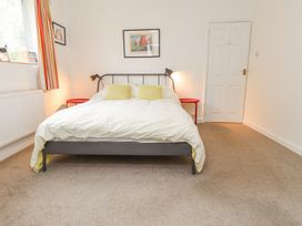 A bedroom with a bed with polka dot bedding two pillows two red side tables and a window at 3 Glyn Y Mor in Llanbedrog