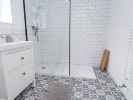 A bathroom with a walk-in shower a white vanity with two drawers and patterned floor tiles at 3 Glyn Y Mor in Llanbedrog