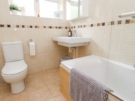 A bathroom with a toilet, sink, bathtub, and towel at 3 Glyn Y Mor in Llanbedrog