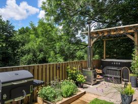 An outdoor deck with a grill and hot tub at The Highwood Hut near Liskeard