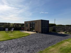 A container structure in a grassy area at Caban in Dothan near Gwalchmai