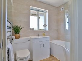 A bathroom with a toilet sink cabinet bathtub and a potted plant at Seascape Cottage in Beer