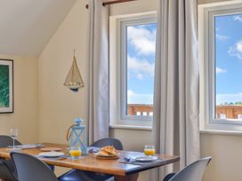 A dining table with plates glasses of orange juice and croissants near windows with curtains at Seascape Cottage in Beer
