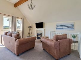 A living room with two brown sofas a fireplace and a television at Seascape Cottage in Beer