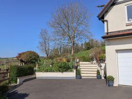 The exterior of a house with stairs leading to a garden with trees and shrubs at Seascape Cottage in Beer