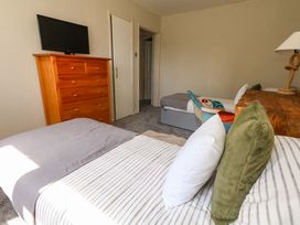 A bedroom with a bed, dresser, television and door at Lily's Pad in Weston, Portland