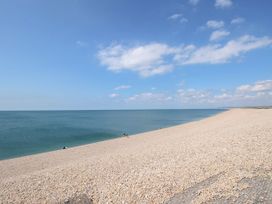 A beach with pebbles and sea under a clear sky at Lily's Pad in Weston, Portland