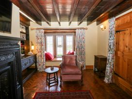 A cozy sitting area with a wooden ceiling beam and a window seat with cushions at Pagecroft Cottage in Haydon Bridge