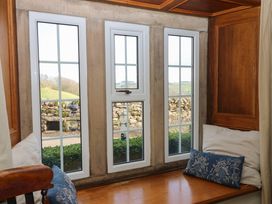A window seat with cushions and a view of a stone wall and countryside at Pagecroft Cottage in Haydon Bridge