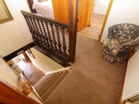 A carpeted stairway landing with a floral upholstered armchair and wooden railings at Pagecroft Cottage in Haydon Bridge