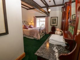 A bedroom with a bed pillows curtains a chair wooden furniture and folded towels at Pagecroft Cottage in Haydon Bridge